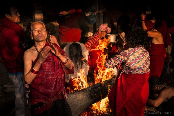 Hindu pilgrims warming themselves by burning fires after taking their holy bath.