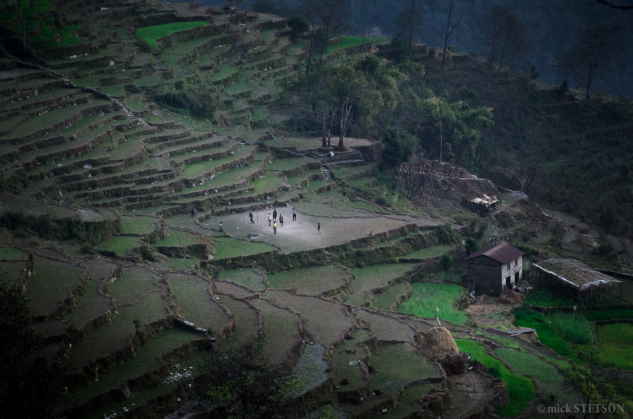 young boys from an Himalayan village playing soccer in an abandoned rice field