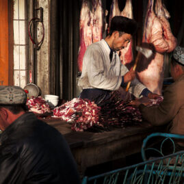Uyghur butcher cutting meat on the street of Kashgar.