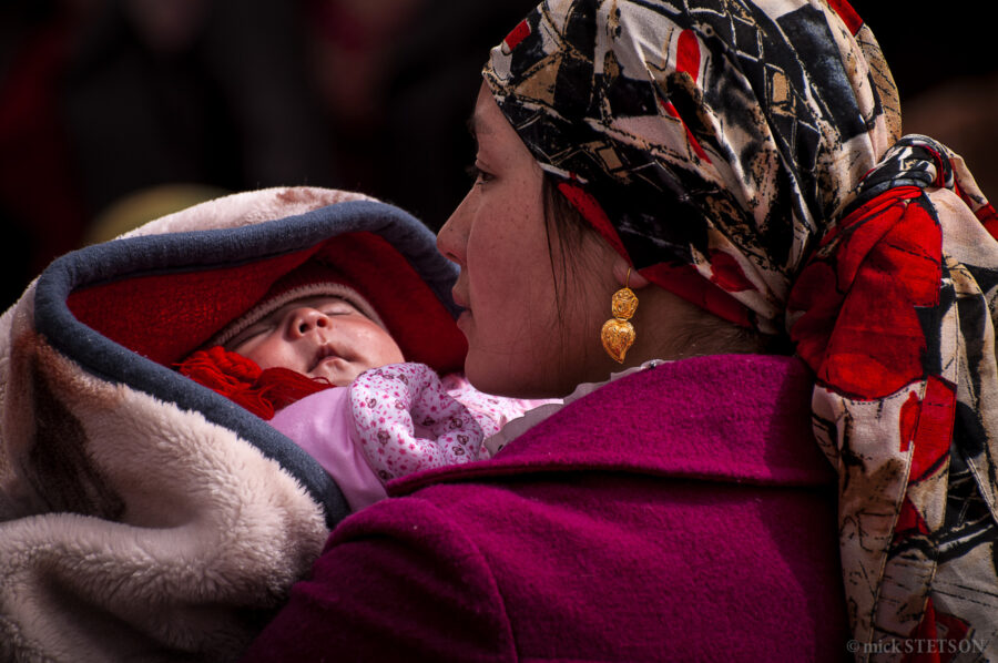 Uyghur mother holding her baby in an open market.