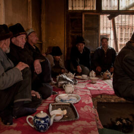 Uyghur men drinking tea and eating flat bread in a traditional tea house.