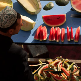 A Uyghur fruit vendor selling watermelon in an open market.