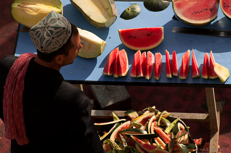 A Uyghur fruit vendor selling watermelon in an open market.